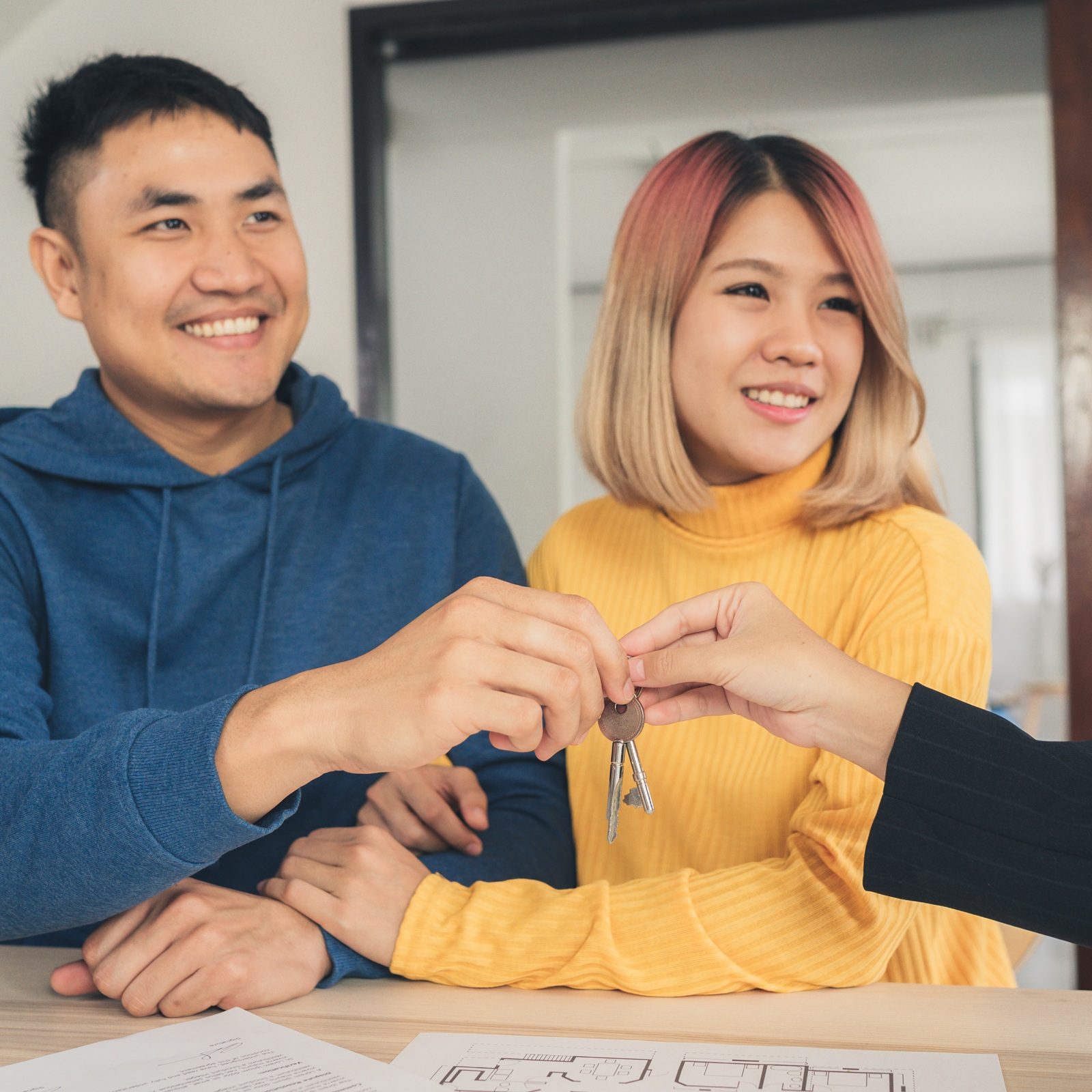 A young couple smiling while receiving keys during a closing meeting.
