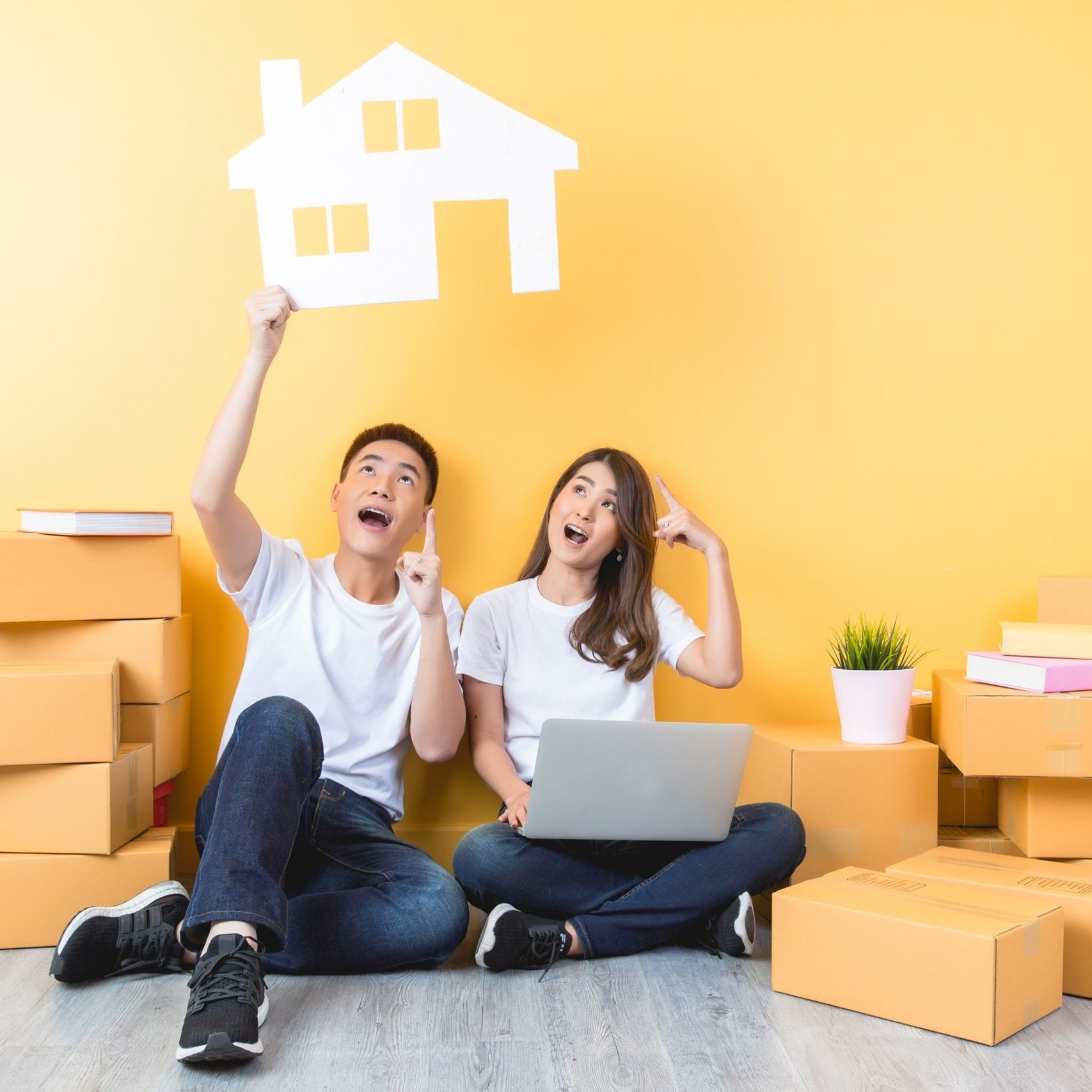 Couple celebrating in an empty room with moving boxes.